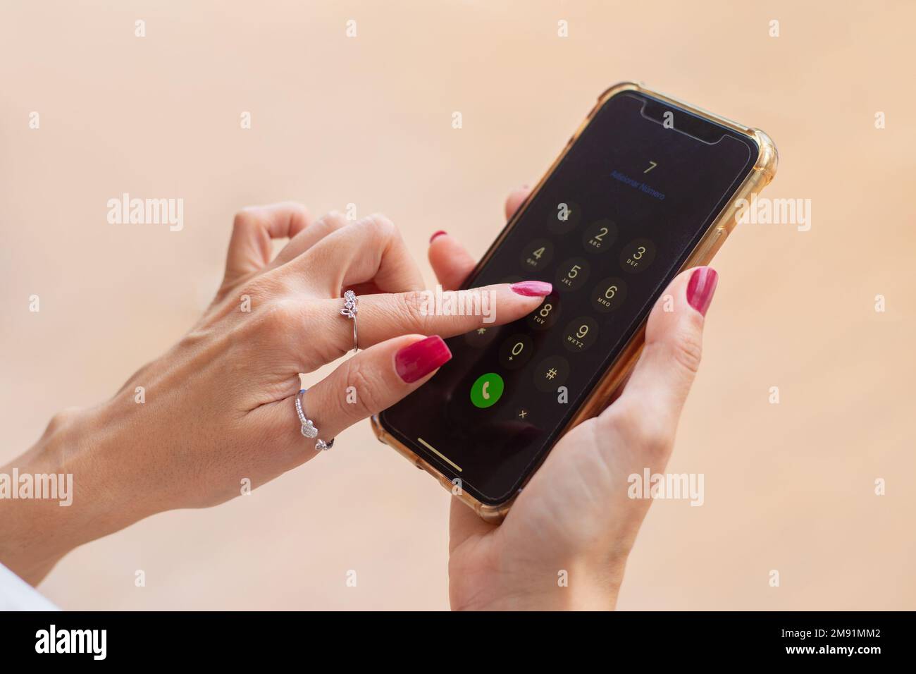 Goiania, Goiás, Brasile – 10 gennaio 2023: Dettaglio delle mani femminili, con chiodi dipinti di rosso, tenendo un telefono cellulare, componendo un numero. Foto Stock