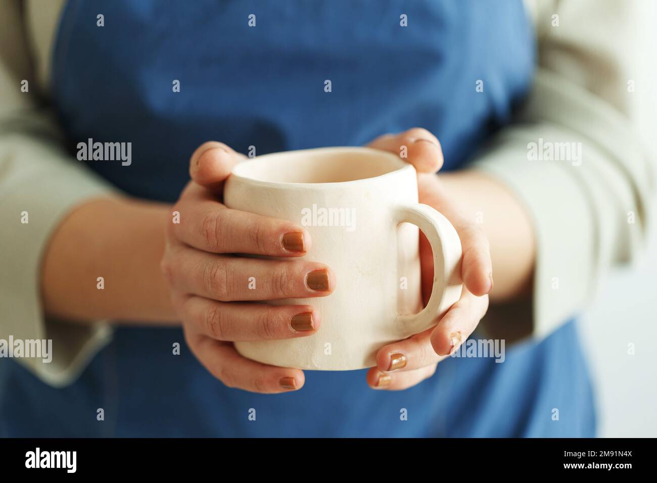 Una donna artigianale irriconoscibile tiene in mano una tazza di ceramica fatta a mano. Piccola impresa. Foto Stock