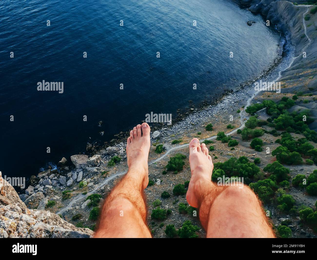 piedi dell'uomo seduto liberamente sulla natura di alta montagna sul mare durante le vacanze estive Foto Stock