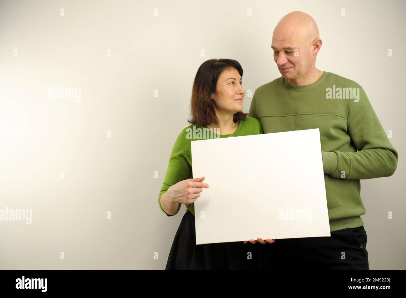 coppia che tiene la bandiera adulto uomo modesto e la donna in vestiti verdi tengono il manifesto davanti loro Foto Stock