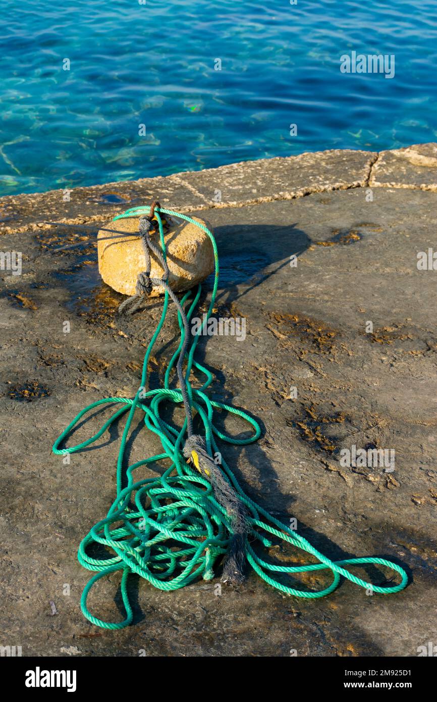Ormeggio in pietra e funi su un molo di cemento, vicino al mare Foto Stock