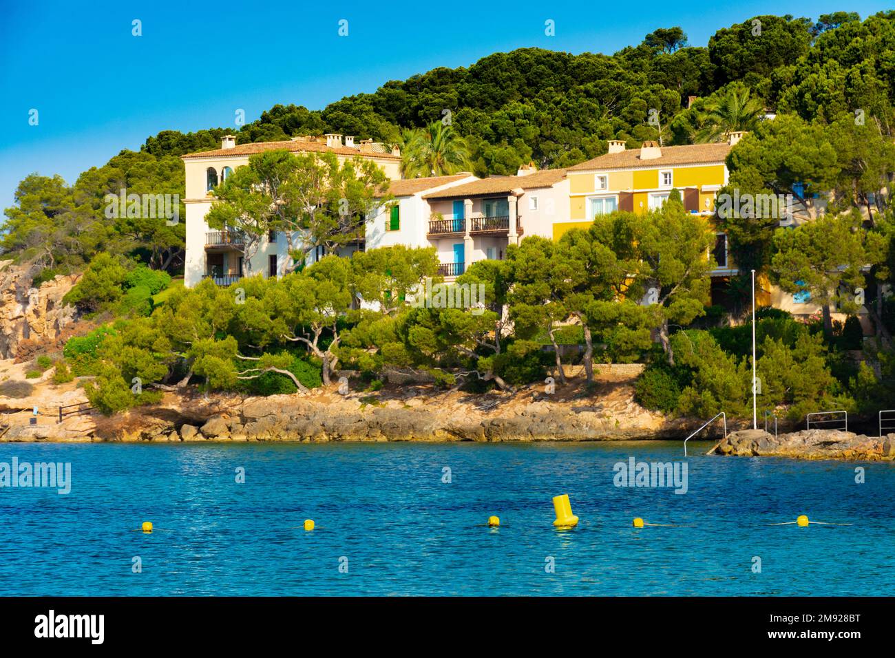 Appartamenti e piccoli villaggi in una pineta nella costa rocciosa della baia di Xinxell, a Maiorca, Spagna Foto Stock
