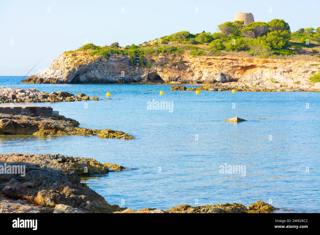 Costa rocciosa della baia di Xinxell, a Ses Illetes a Maiorca, sullo sfondo l'isola di SA torre con la sua torre Foto Stock