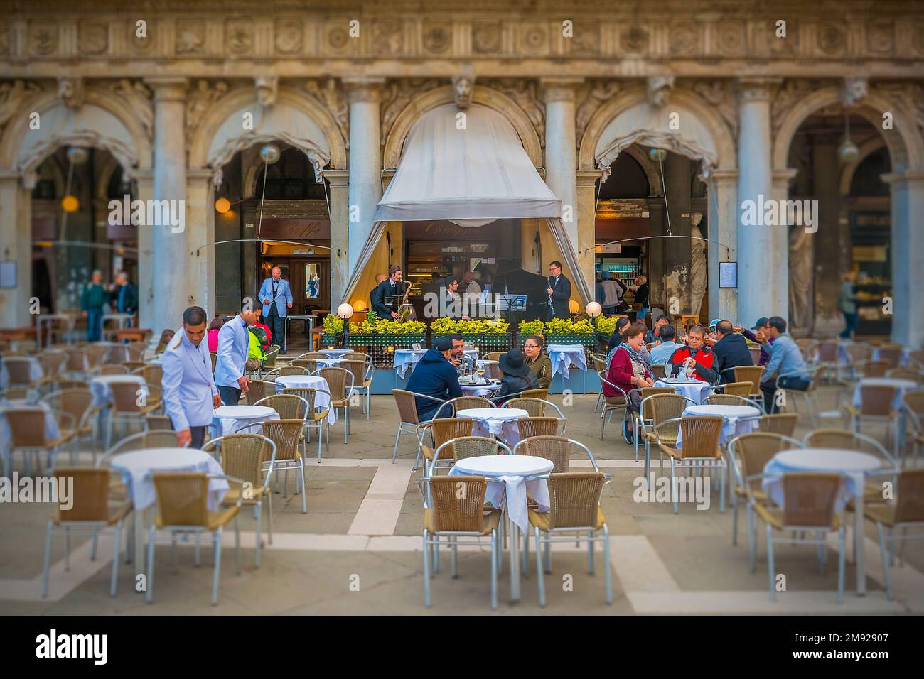 I camerieri puliscono i tavoli al leggendario caffe Florian con la caffe Florian Orchestra sullo sfondo, su St Piazza Marco a Venezia. Foto Stock