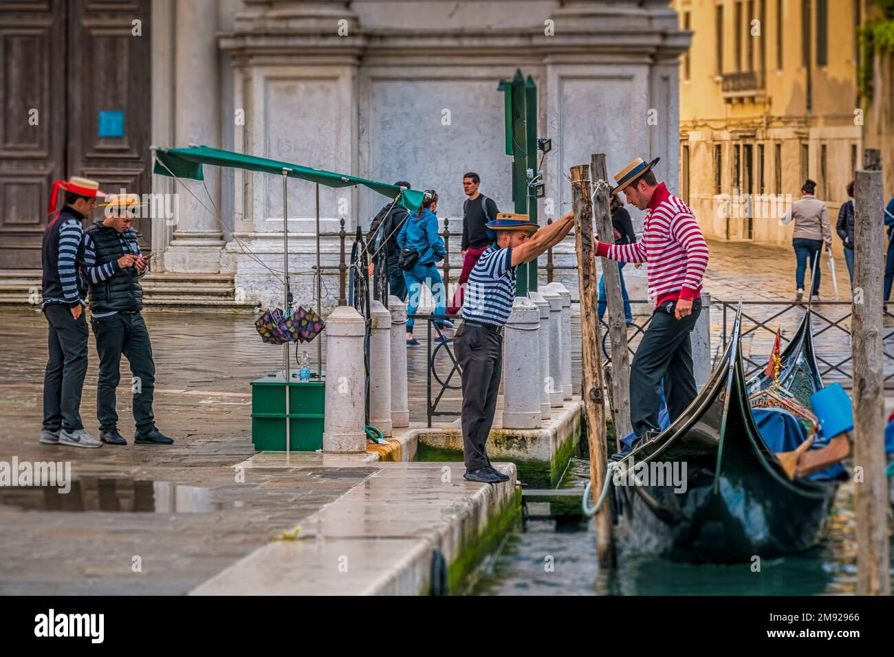 Gondolieri veneziani nel loro tradizionale vestito in una sosta in Gondola vicino all'Accademia di Venezia Foto Stock