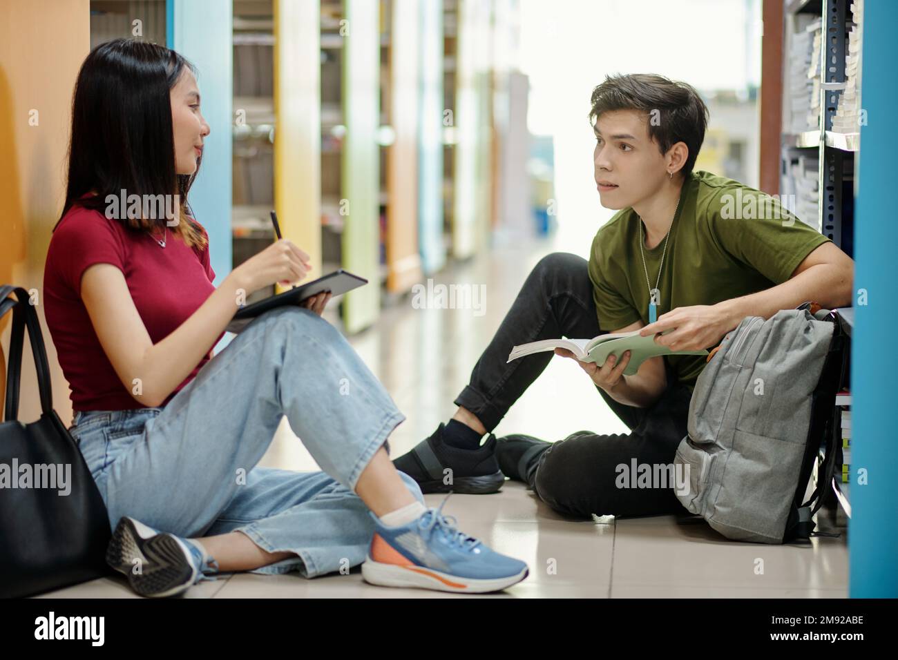Studenti delle scuole superiori seduti al piano della biblioteca e che discutono del progetto Foto Stock