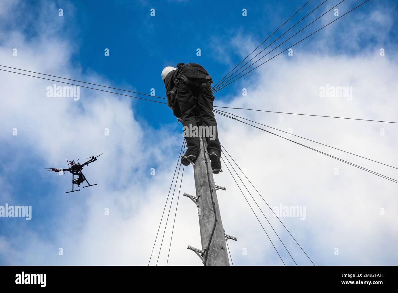 Telecomunicazioni,ingegnere di telecomunicazioni che lavora su palo telegrafo con drone che vola sopra. Tecnologia dei droni, banda larga, 5g, internet... concetto. REGNO UNITO Foto Stock