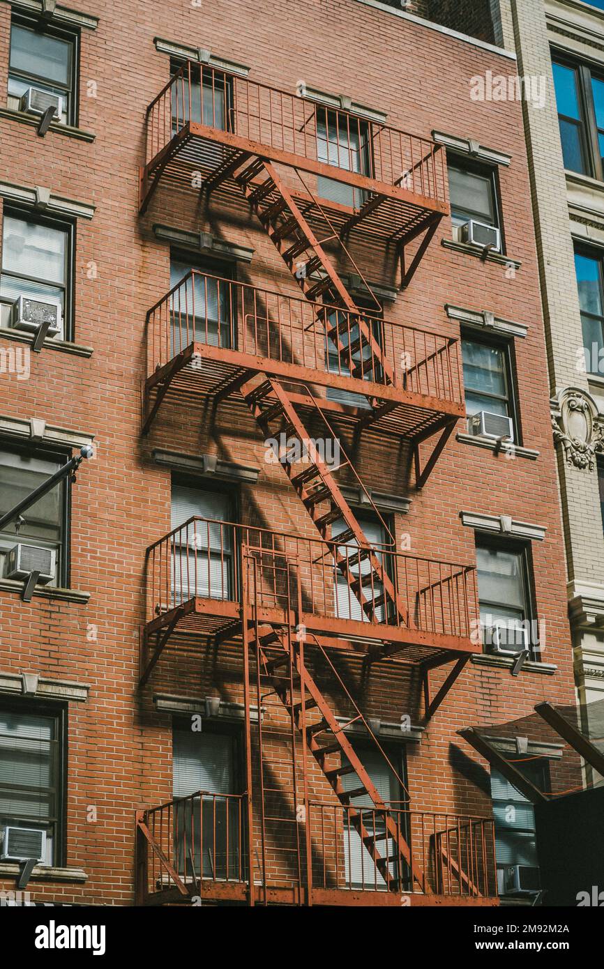 Dal basso si può vedere il vecchio edificio in mattoni di New York con scale di fuga fuori fuoco negli Stati Uniti Foto Stock