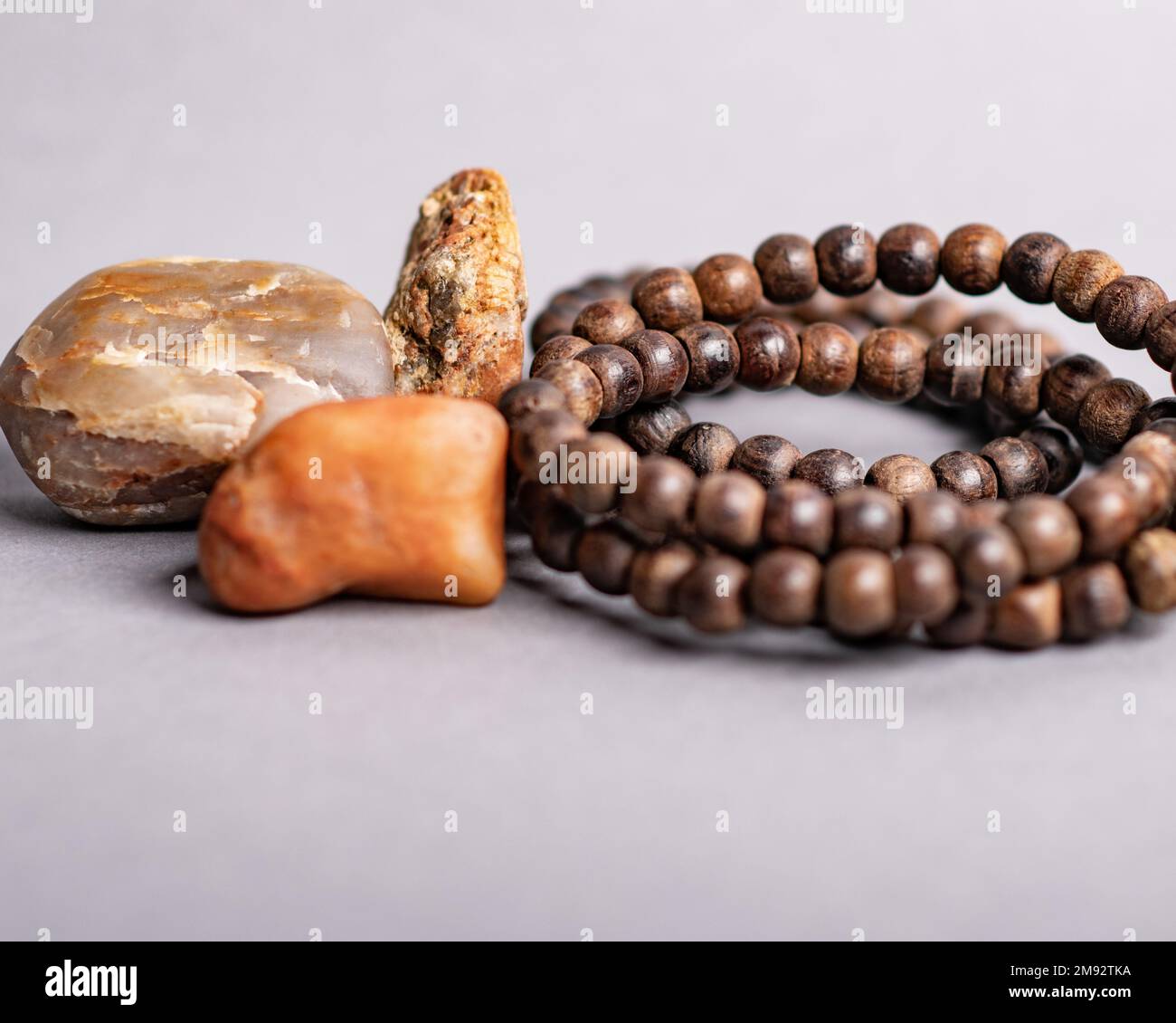 Le perline di preghiera in legno di Mala, poste vicino alle pietre, isolate su sfondo viola Foto Stock