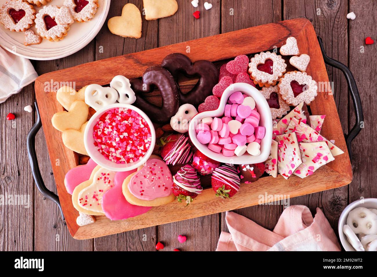 Dolci e biscotti di San Valentino. Vista dall'alto in un vassoio di servizio su uno sfondo di legno. Tema amore e cuori. Foto Stock