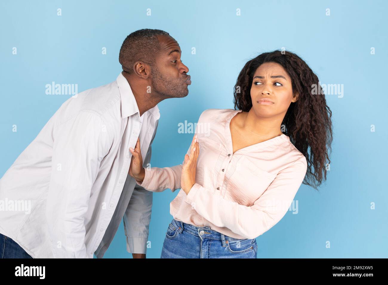 Concetto di Friendzone. Giovane donna nera disgustata evitando bacio indesiderato da parte di un uomo di mezza età Foto Stock