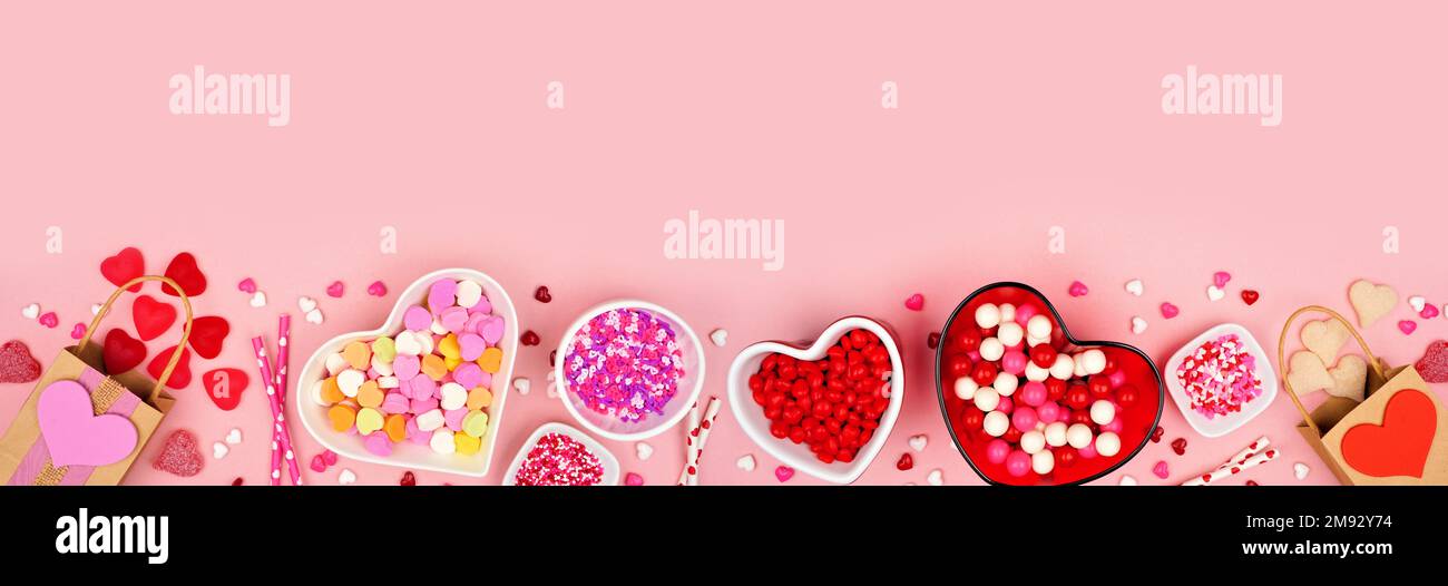 San Valentino caramella bordo inferiore con una selezione di dolci. Vista dall'alto verso il basso su uno sfondo di carta rosa con spazio per la copia. Foto Stock