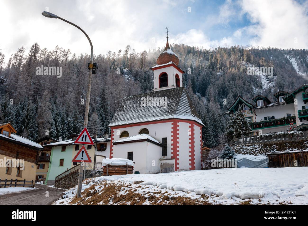 Neve fresca del mattino sui tetti dei cottage e Chiesa di San Giuseppe, Dolomiti, Moena, Italia Foto Stock