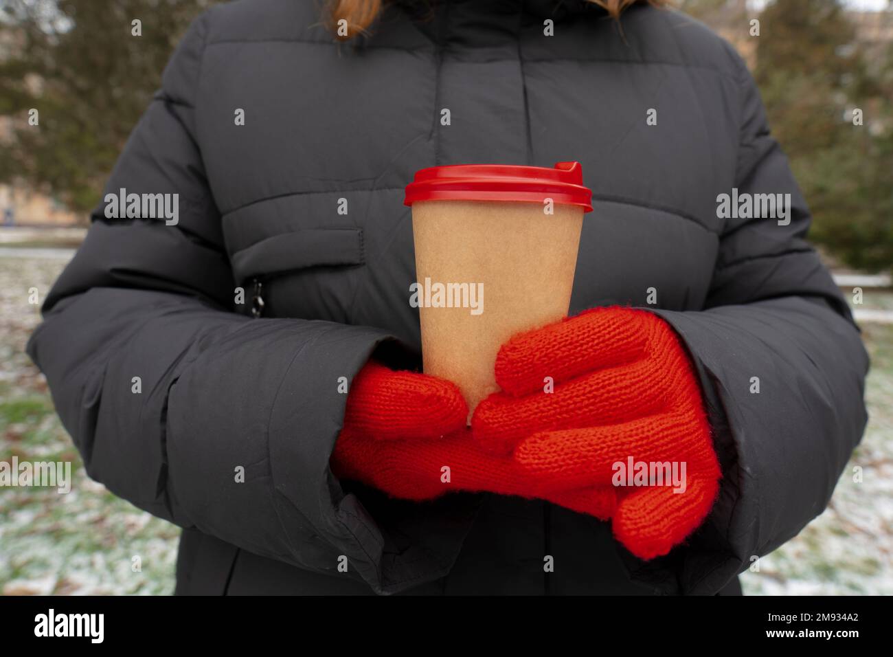 Inverno. Clima freddo. Parco cittadino. La ragazza tiene in mano una tazza di caffè (primo piano). Stile di vita. Passeggiate all'aperto Foto Stock