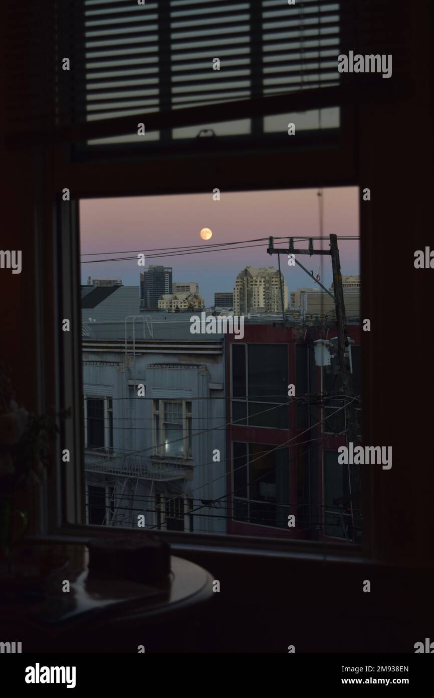 La luna davanti ad un tramonto dalla mia finestra. Foto Stock