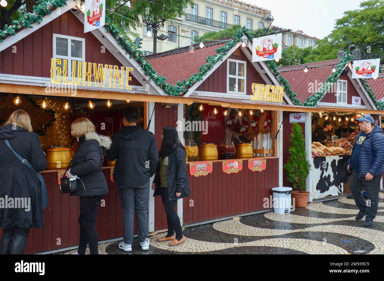 Mercato di Natale di Rossio in Piazza Rossio a Lisbona, Portogallo. I visitatori che provano del vino alla stalla Gluhwine. Novembre 2022. Foto Stock