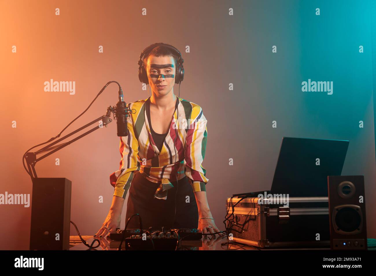 Artista musicale con pazzo make up aver partito per mixare dischi e canzoni techno ai tavoli da concerto in studio. Uso del mixer per eseguire con apparecchiature audio e strumenti stereo, elettronica. Foto Stock