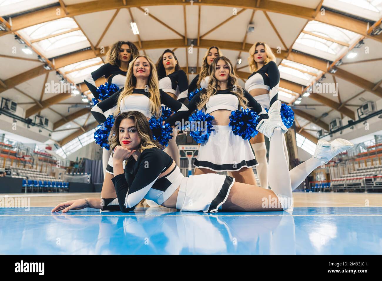 Inquadratura a basso angolo di cheerleaders in tre file, sdraiati, inginocchiati e in piedi. Concetto sportivo. Foto di alta qualità Foto Stock