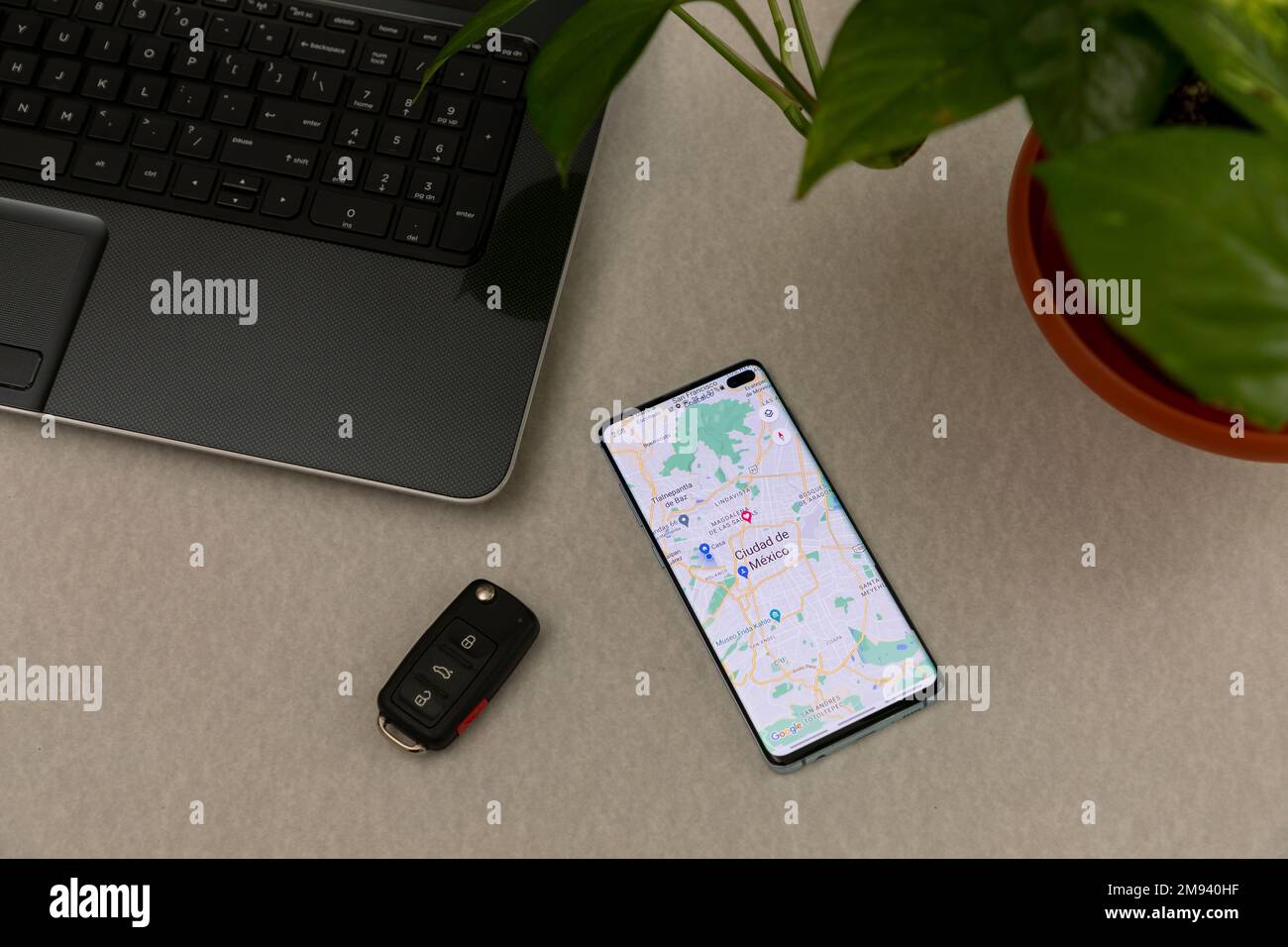 Messico, CDMX - 01 maggio 2022: Applicazione Google Maps su uno schermo del telefono cellulare su una scrivania, con un computer portatile, un fioraio e chiavi dell'auto. Foto Stock