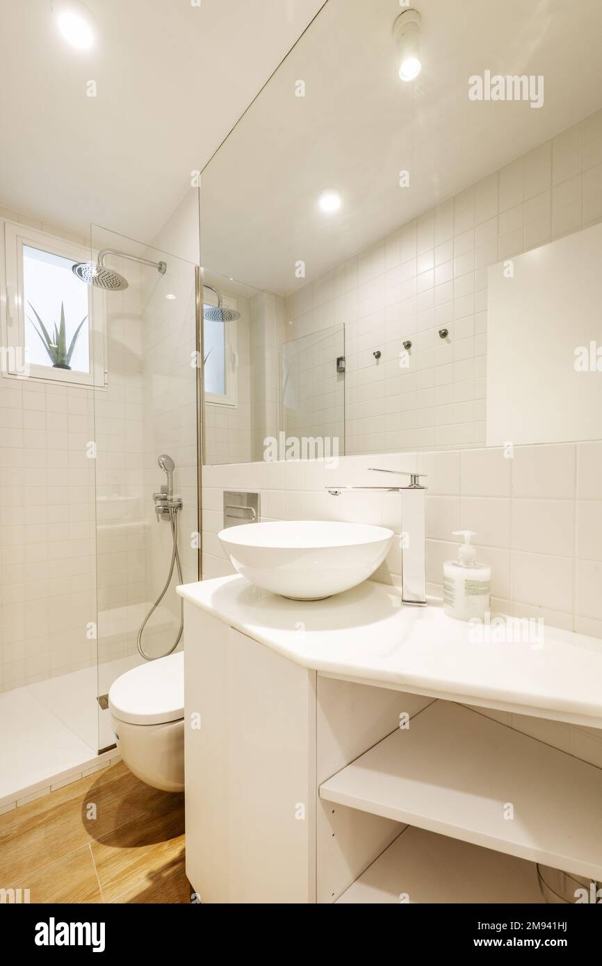 Bagno con armadi in legno bianco, lavabo emisferico in porcellana bianca,  grande specchio da incasso e box doccia in vetro Foto stock - Alamy