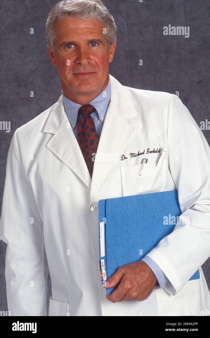 Primo piano ritratto di un vecchio medico di sesso maschile in un camice di laboratorio bianco in possesso di cartelle cliniche Foto Stock