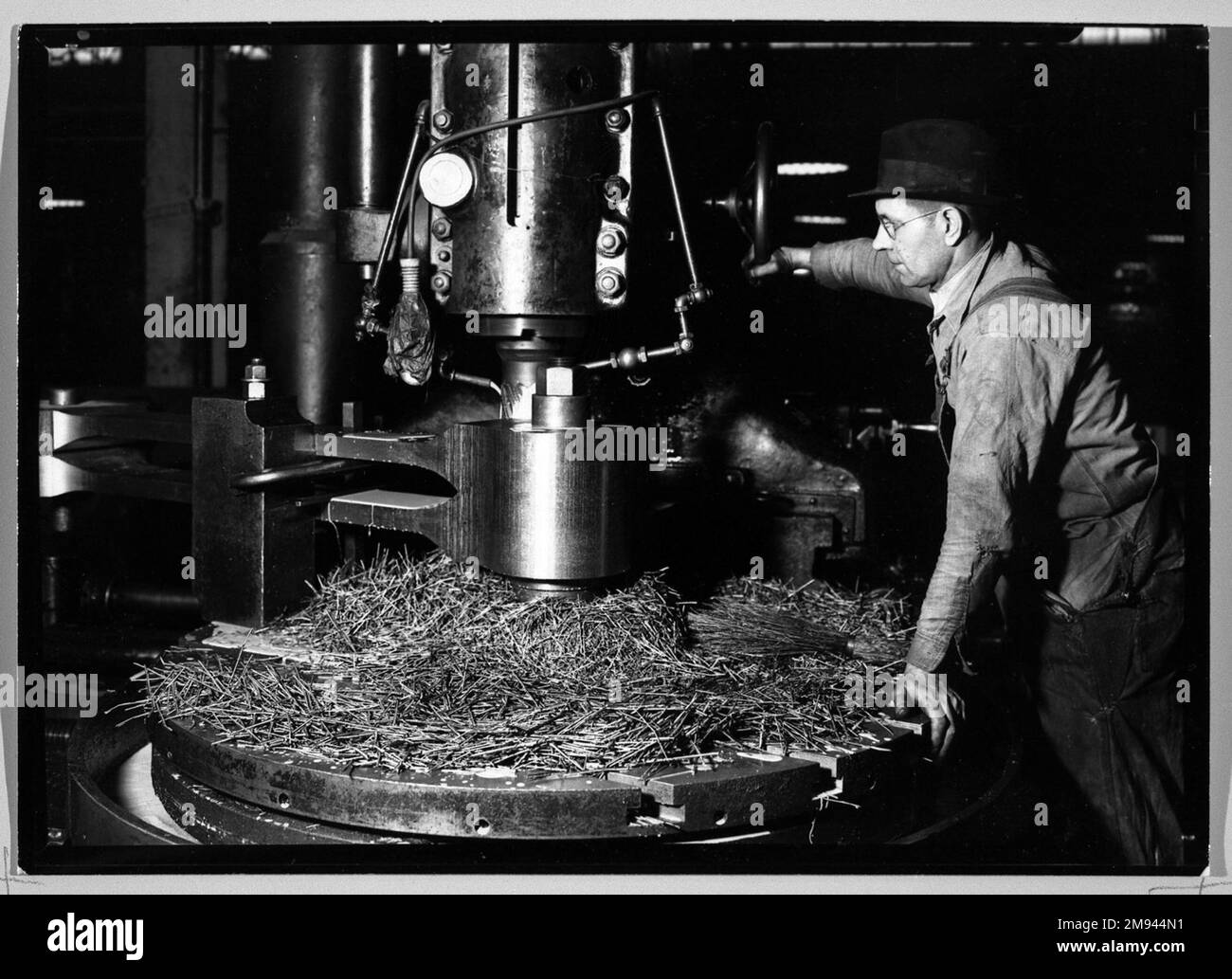 [Untitled] (Man in Hat Standing at Machine) Lewis Wickes Hine (americano, 1874-1940). , 1936-1937. Fotografia in argento gelatina, 4 3/4 x 7 1/4 pollici (12,1 x 18,4 cm). Fotografia 1936-1937 Foto Stock