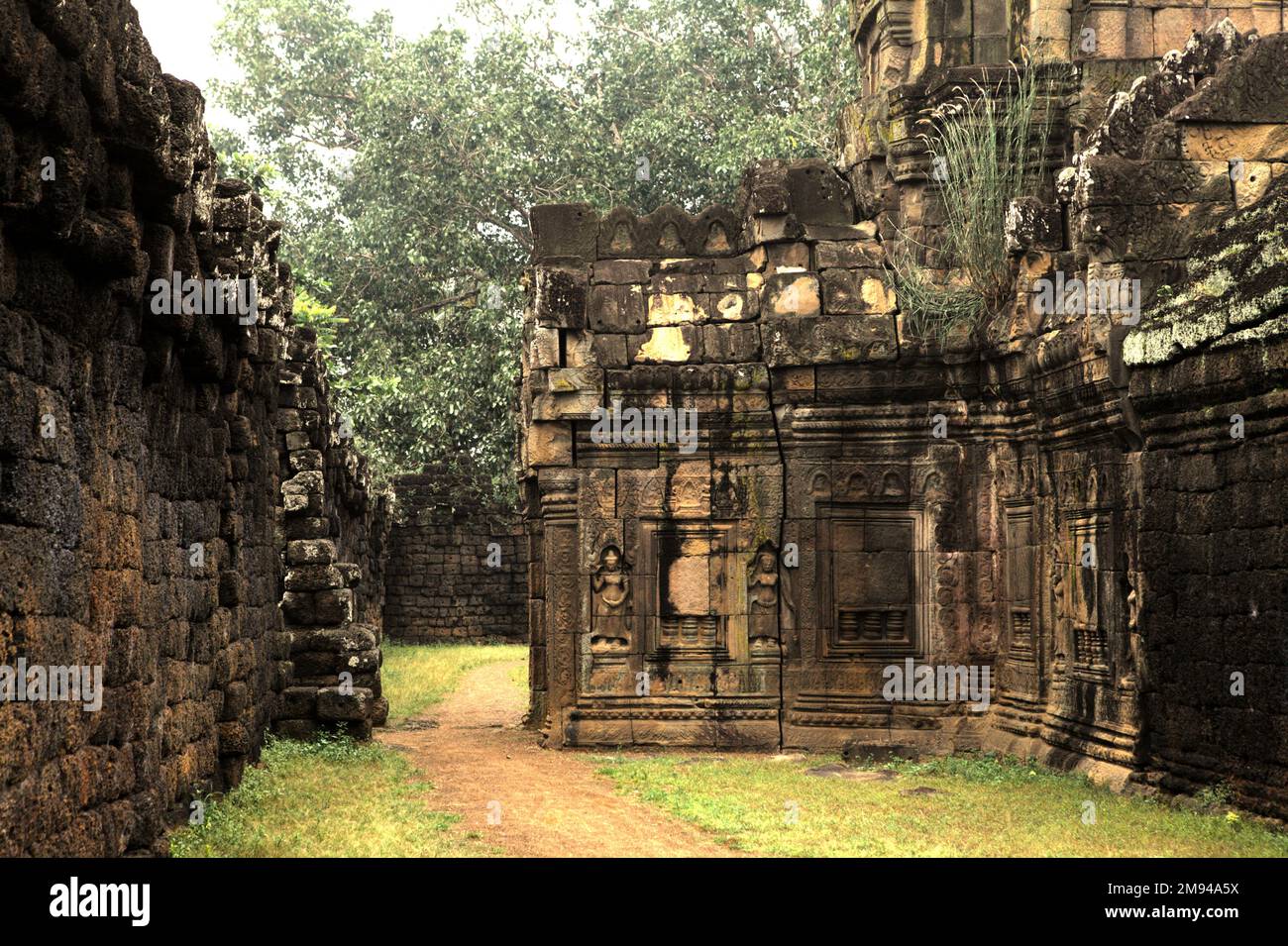 Un passaggio pedonale tra il muro esterno e Banteay Prei Nokor, un tempio raramente touristed 11th ° secolo affiliato al buddismo situato in Kampong Cham (Kompong Cham), Cambogia. "La sostenibilità delle risorse del patrimonio culturale è fortemente legata all'effettiva partecipazione delle comunità locali alla conservazione e alla gestione di queste risorse", ha scritto un team di scienziati guidati da Sunday Oladipo Oladeji nell'abstract del loro documento pubblicato su Sage Journals il 28 ottobre 2022. Foto Stock