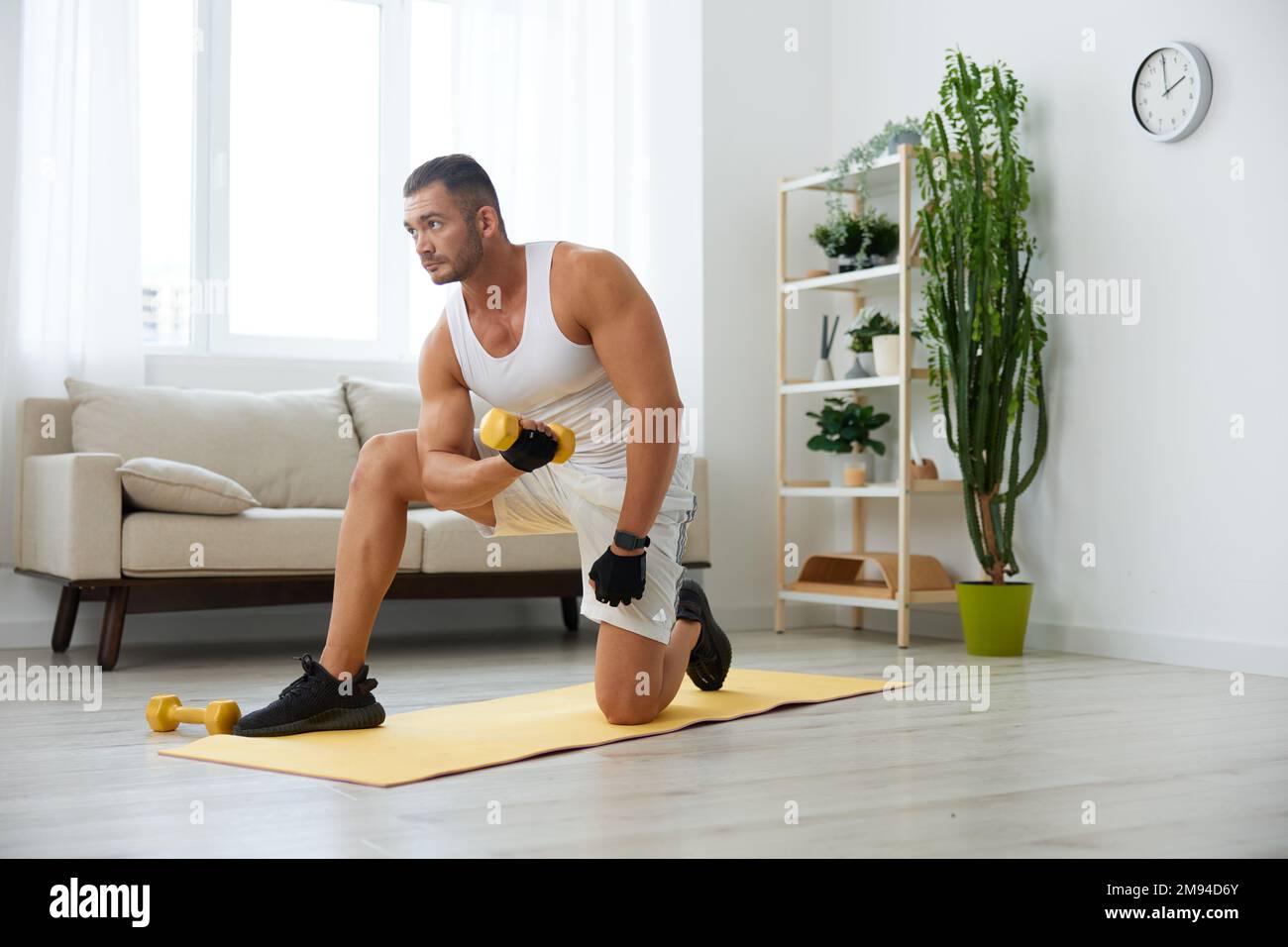 L'uomo sport allenamento domestico sul pavimento su un tappetino con  manubri, esercizi per la crescita muscolare, pompato su uomo fitness  allenatore esercizi a casa, il Foto stock - Alamy
