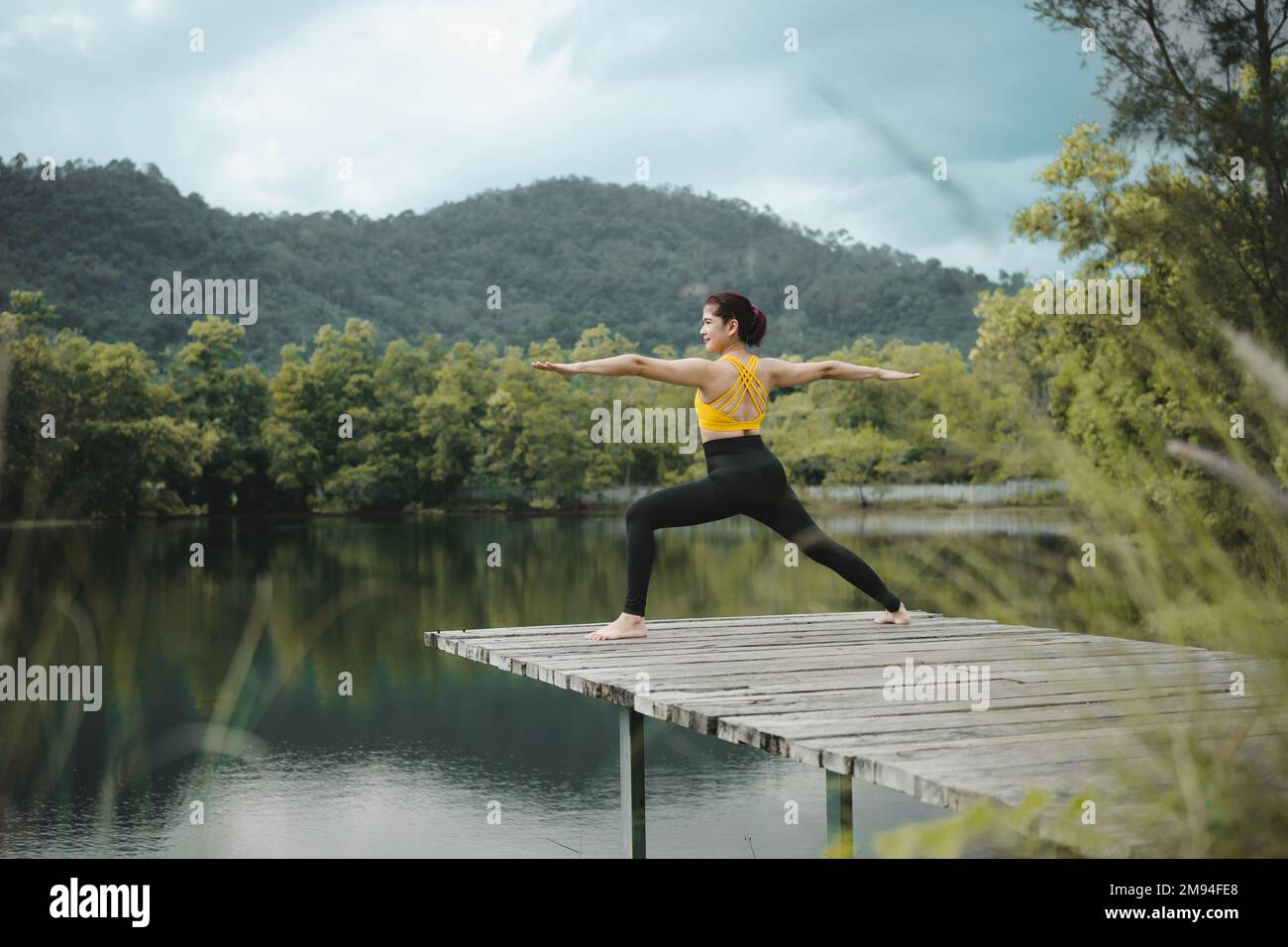 Donna che pratica yoga sul ponte a Lake.Yoga e concetto di stile di vita sano. Foto Stock