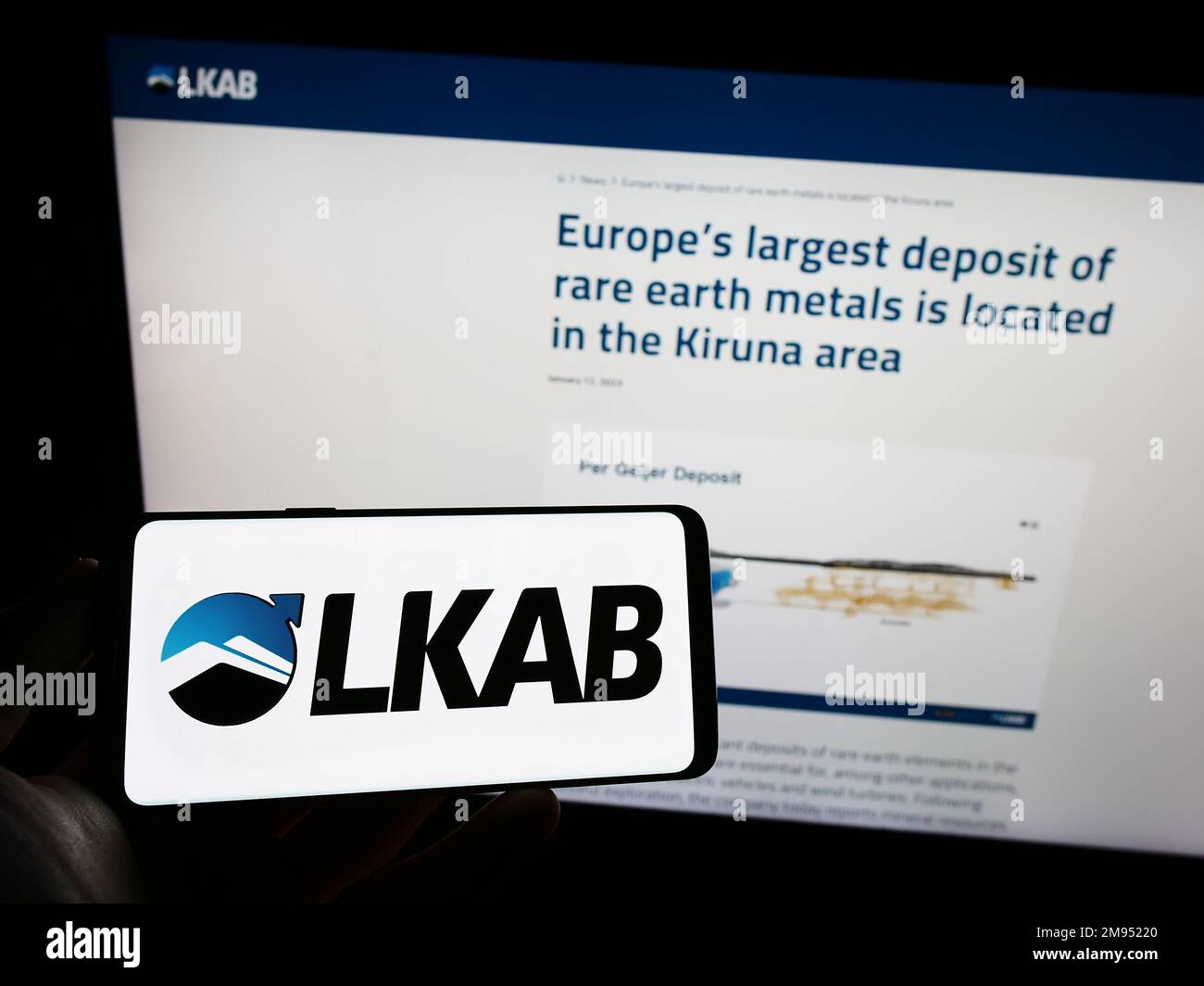 Persona che tiene il cellulare con il logo della società Luossavaara-Kiirunavaara AB (LKAB) sullo schermo di fronte al sito web aziendale. Messa a fuoco sul display del telefono. Foto Stock