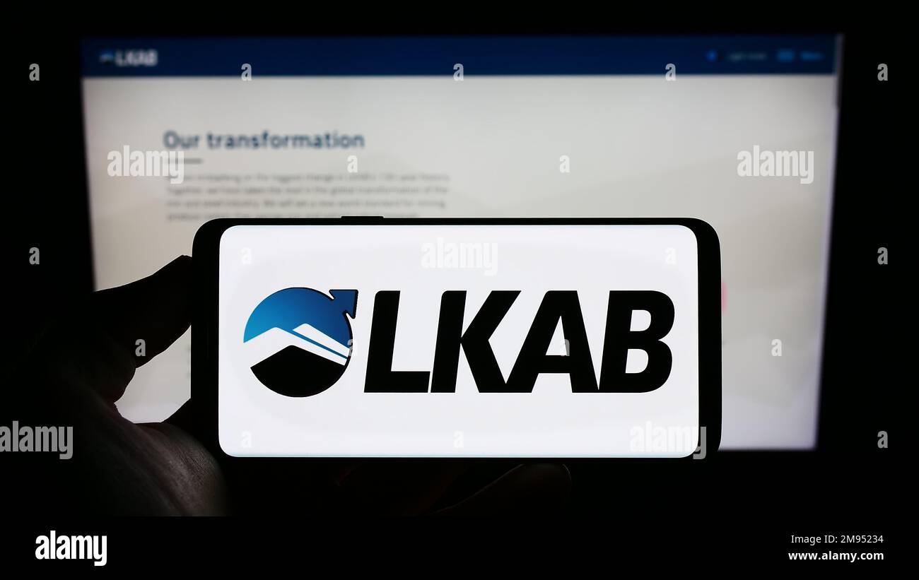 Persona in possesso di smartphone con il logo della società Luossavaara-Kiirunavaara AB (LKAB) sullo schermo di fronte al sito web. Messa a fuoco sul display del telefono. Foto Stock