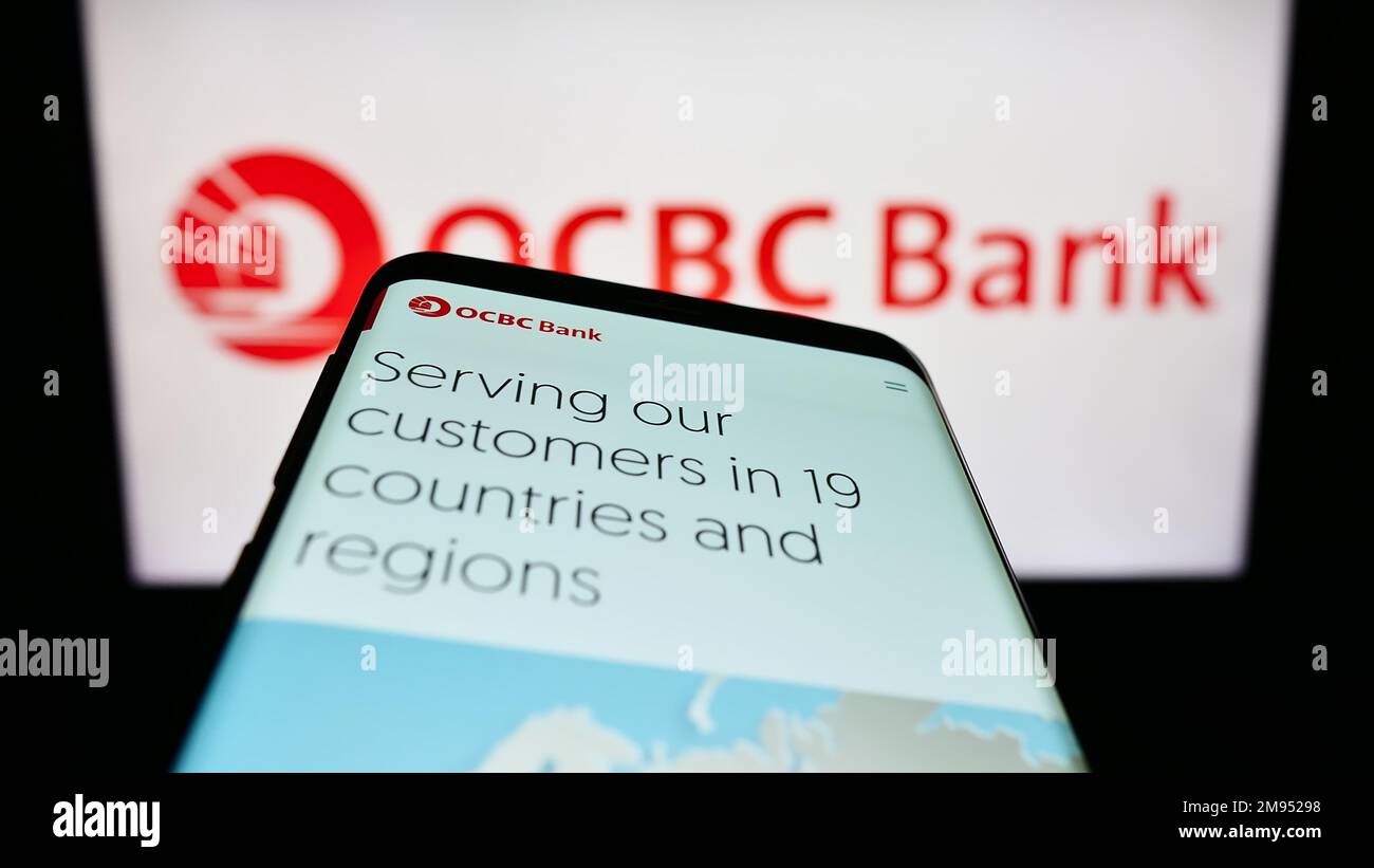 Telefono cellulare con pagina web di Oversea-Chinese Banking Corporation (OCBC Bank) sullo schermo di fronte al logo. Messa a fuoco in alto a sinistra del display del telefono. Foto Stock