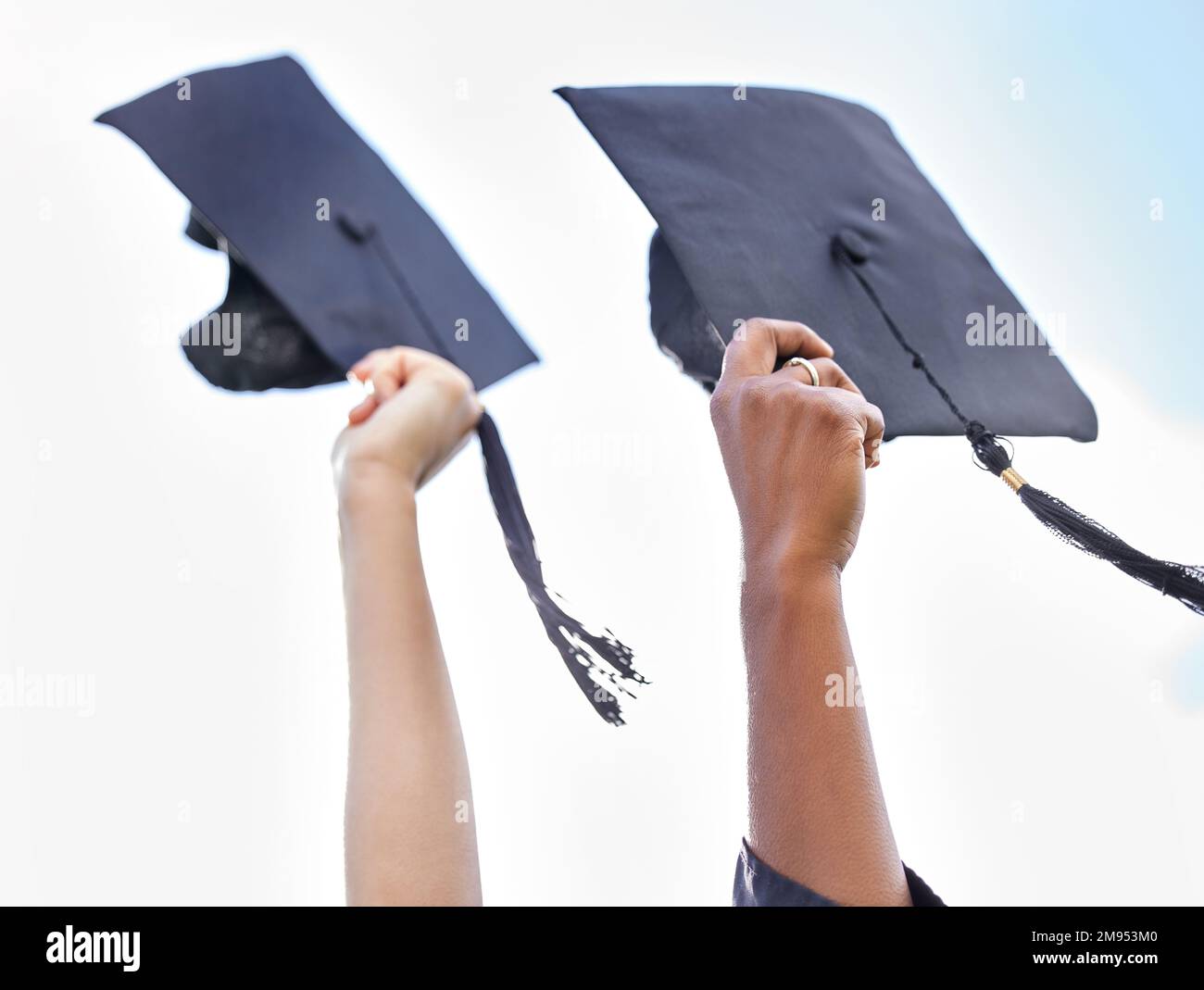Cappelli fuori a voi. Primo piano di due studenti irriconoscibili che tengono il cappello il giorno della laurea. Foto Stock