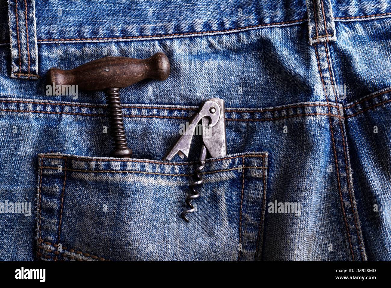 vecchio cavatappi e apribottiglie in una tasca posteriore di jeans blu Foto Stock