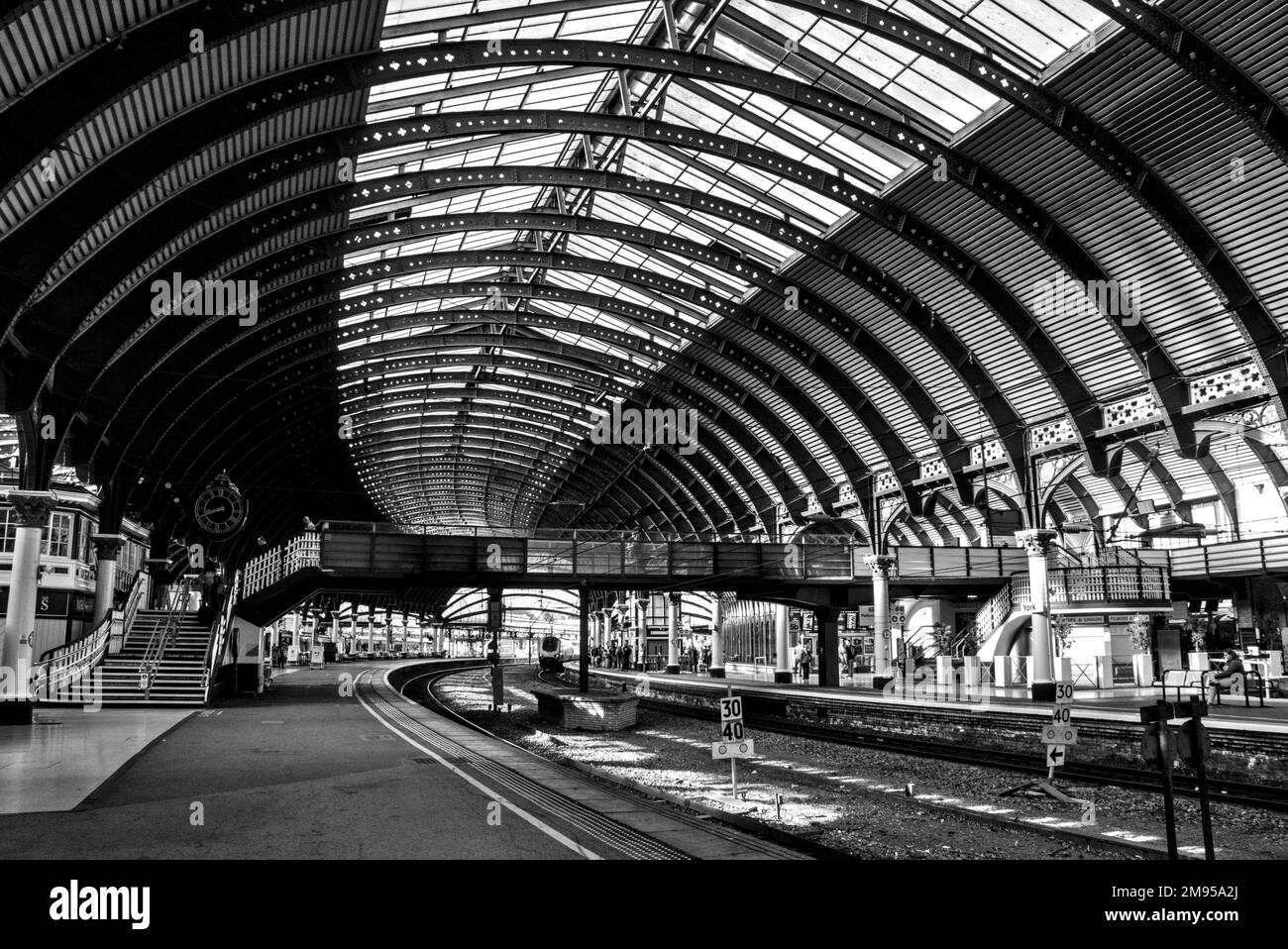 Una scala di grigi all'interno della stazione di transito di York in Inghilterra con una ferrovia e tetto ad arco Foto Stock