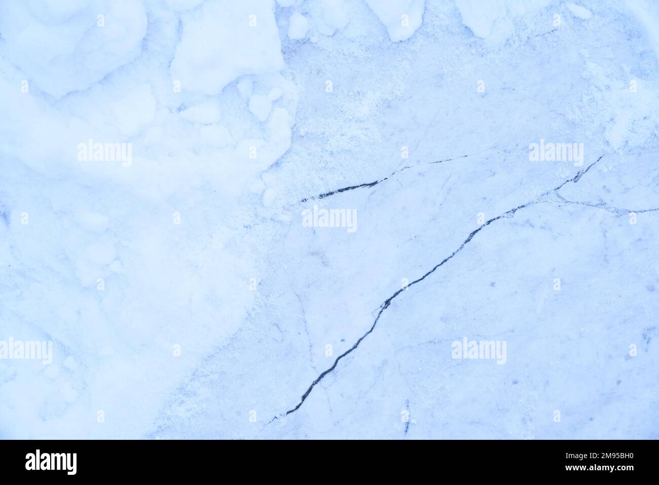 Un pezzo di neve spaccata. La struttura è una superficie di marmo blu opaco con pezzi di neve. Gelo invernale, sfondo di pavimento di marmo congelato. Foto di alta qualità Foto Stock