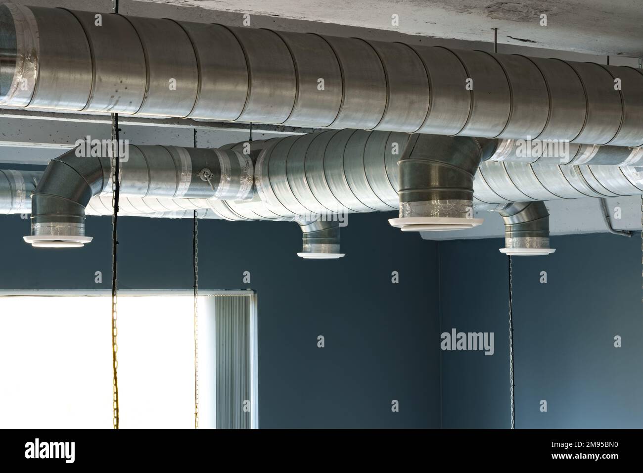Tubi di ventilazione in argento appesi al soffitto all'interno dell'edificio Foto Stock