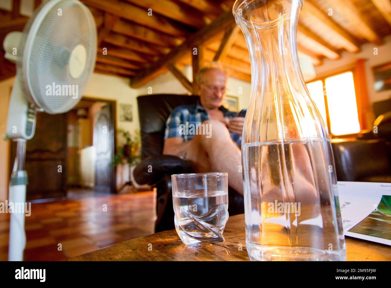 Anziani e ondata di calore: Rimanere idratati. Calore intenso: Vecchio bere acqua e ventilatore soffiare aria. Illustrazione, persone anziane e idratazione, Foto Stock