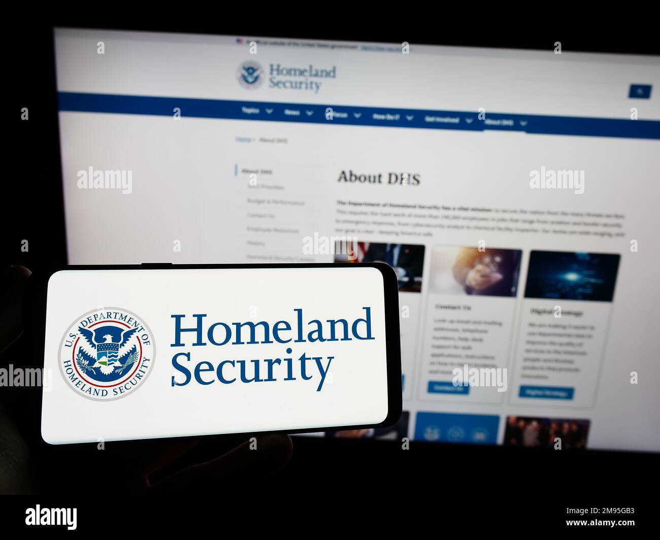 Persona che tiene il cellulare con sigillo del Dipartimento di sicurezza interna degli Stati Uniti (DHS) sullo schermo di fronte al sito web. Messa a fuoco sul display del telefono. Foto Stock