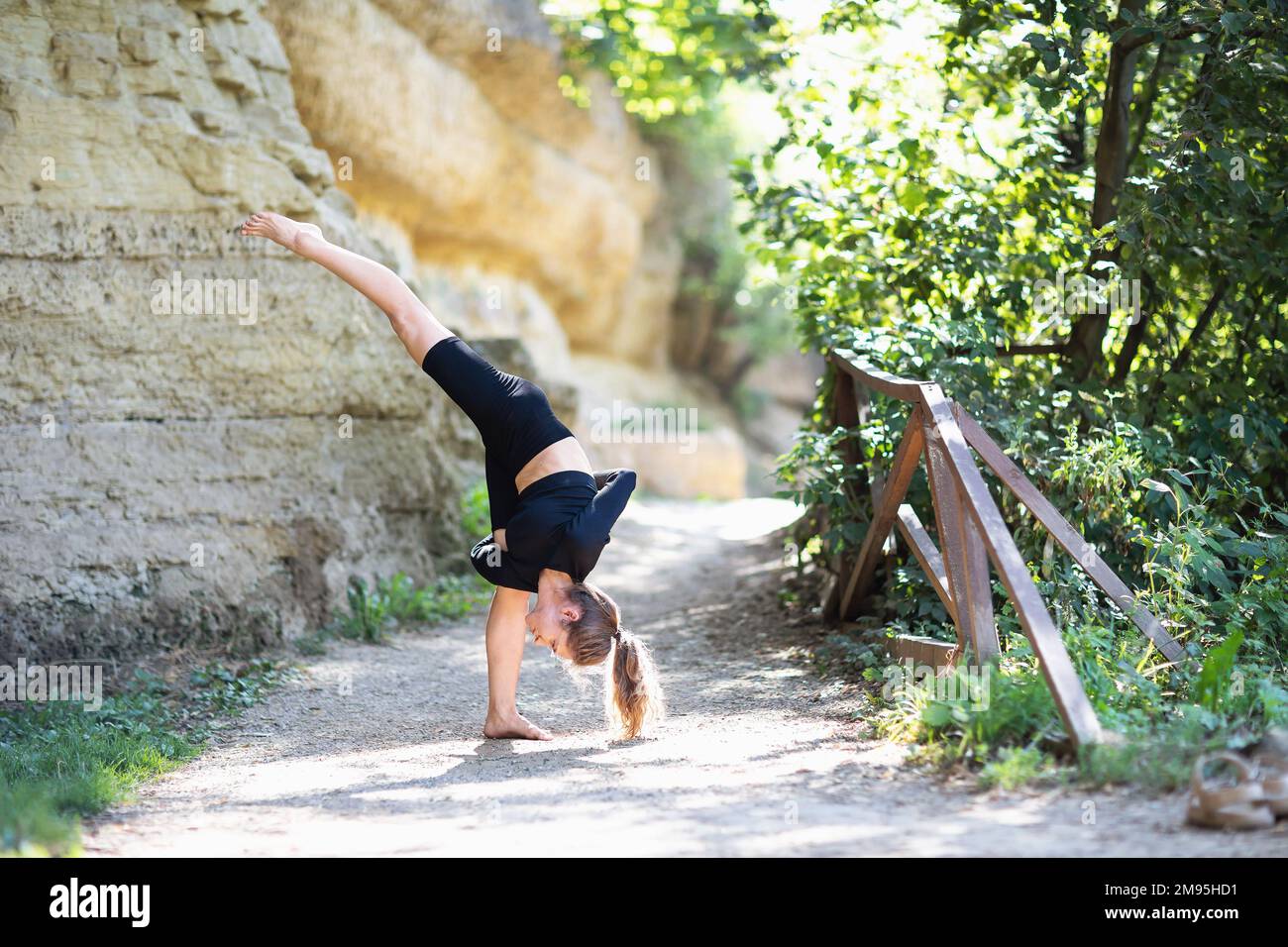 Una giovane donna che conduce uno stile di vita sano e pratica yoga, esegue l'esercizio Urdhwa Prasarita Ekapadasana, un tilt con una gamba distesa, tr Foto Stock