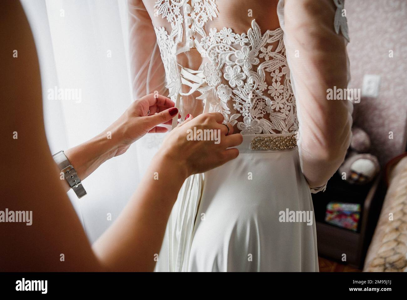 bridesmaid legando un nastro su elegante, possibile matrimonio bianco abito bridesmaid Foto Stock