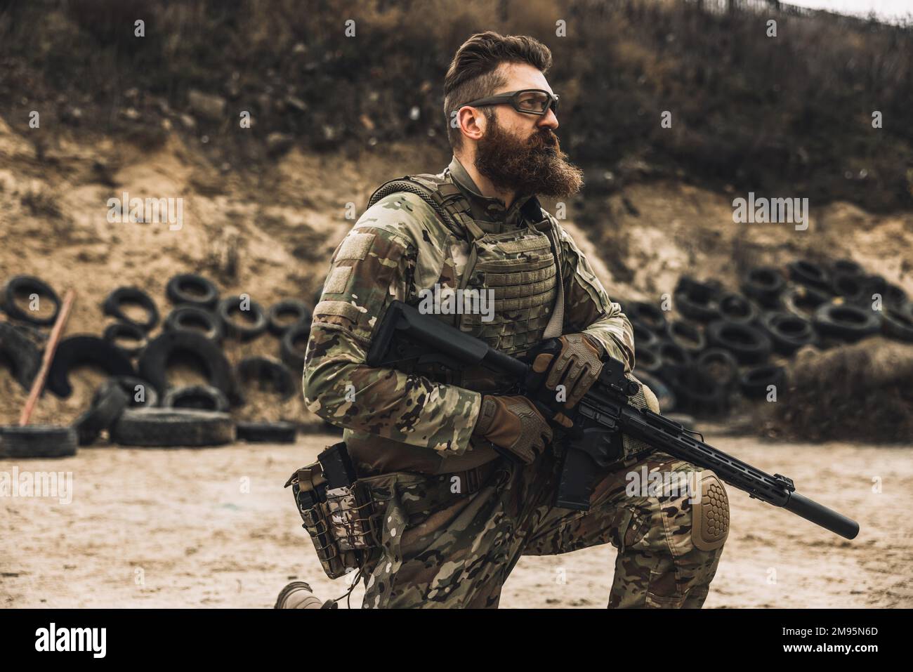 Uomo bearded dai capelli scuri in uniforme militare che guarda determinato Foto Stock