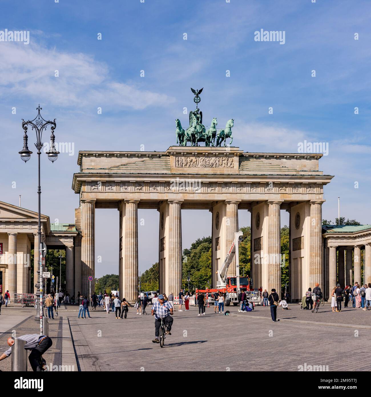 La porta di Brandeburgo con lampione stradale e gente come punto di riferimento tedesco sotto il cielo blu, Berlino, Germania Foto Stock