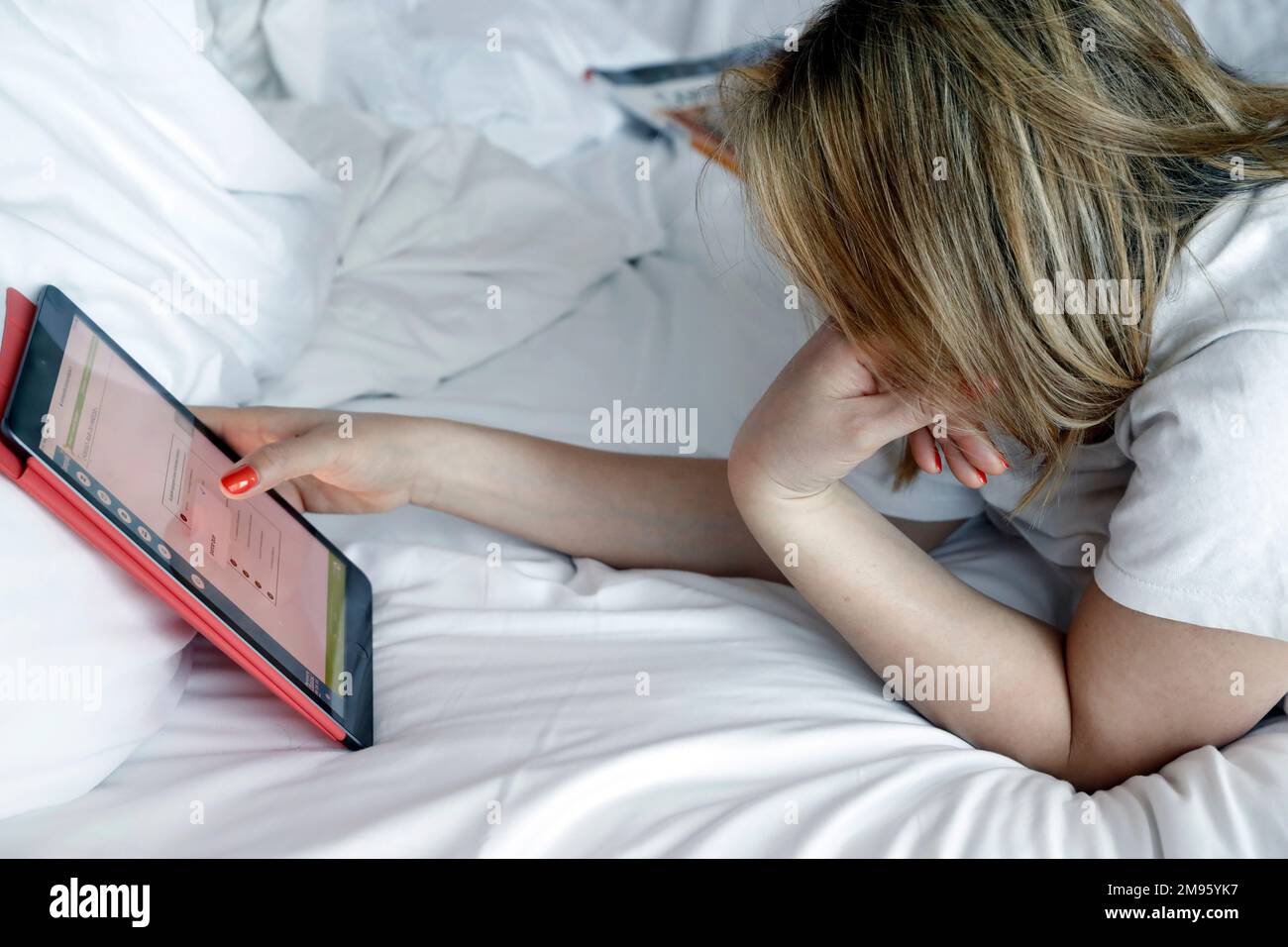 Donna che usa un tablet a letto. Concetto di shopping digitale. Foto Stock