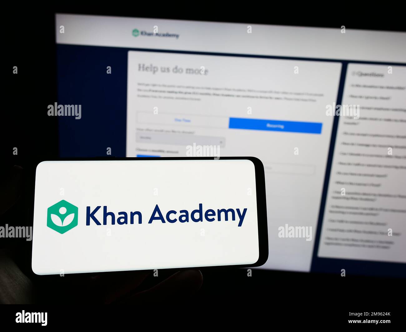 Persona che tiene il telefono cellulare con il logo della società di istruzione non-profit Khan Academy Inc. Sullo schermo di fronte alla pagina web. Messa a fuoco sul display del telefono. Foto Stock