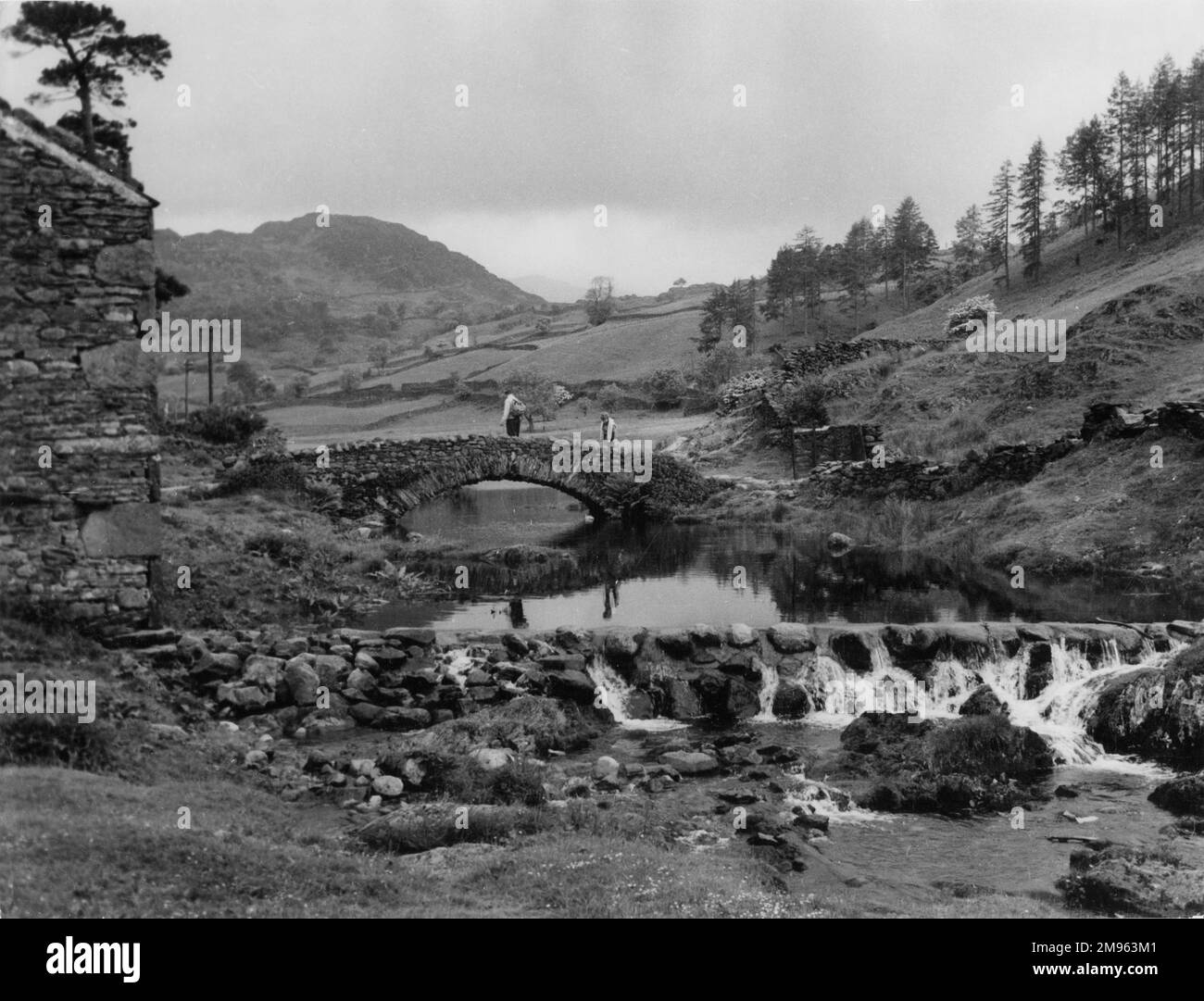 Una scena tranquilla vicino al torrente Lodore, con il suo vecchio ponte di pietra che lo attraversa, a Watendlath, una frazione remota nella vale di Watendlath, Lake District, Cumbria, Inghilterra. Foto Stock