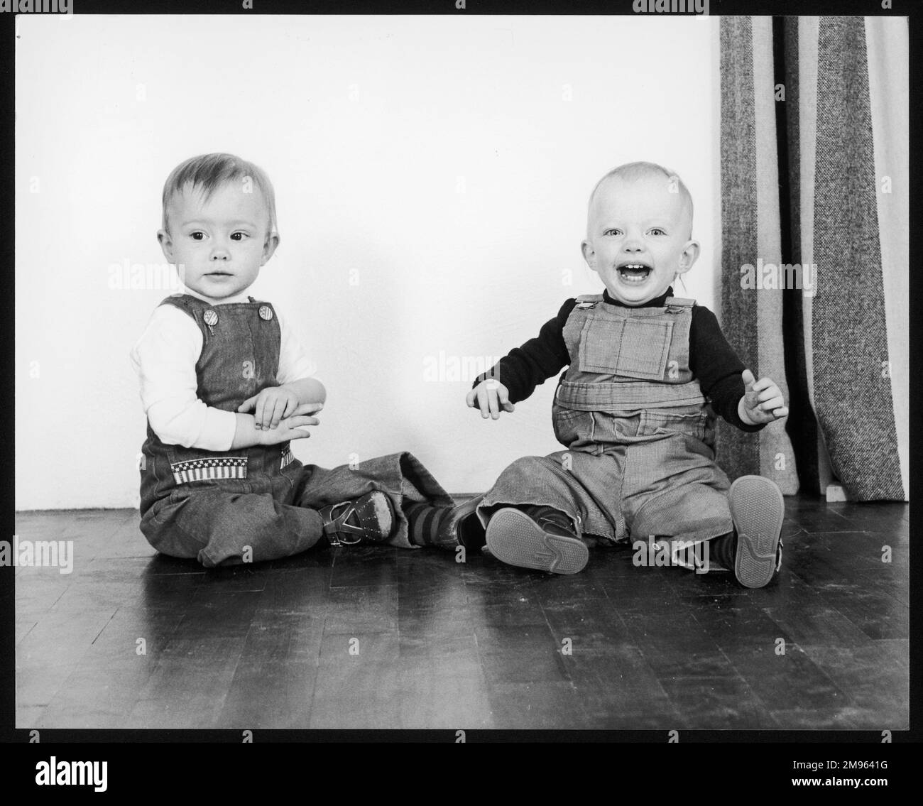 Due bambini in salopette che sono anche sorelle gemelle non identiche Foto Stock