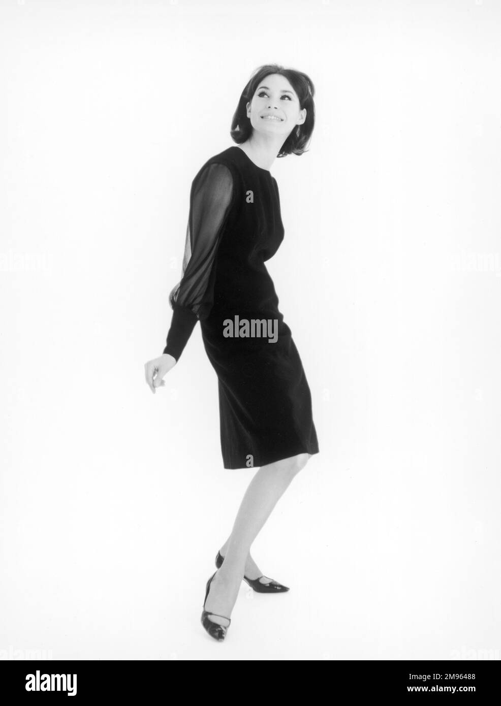 Ritratto a tutta lunghezza di un modello che indossa un abito nero, facendo clic sulle dita. Foto Stock