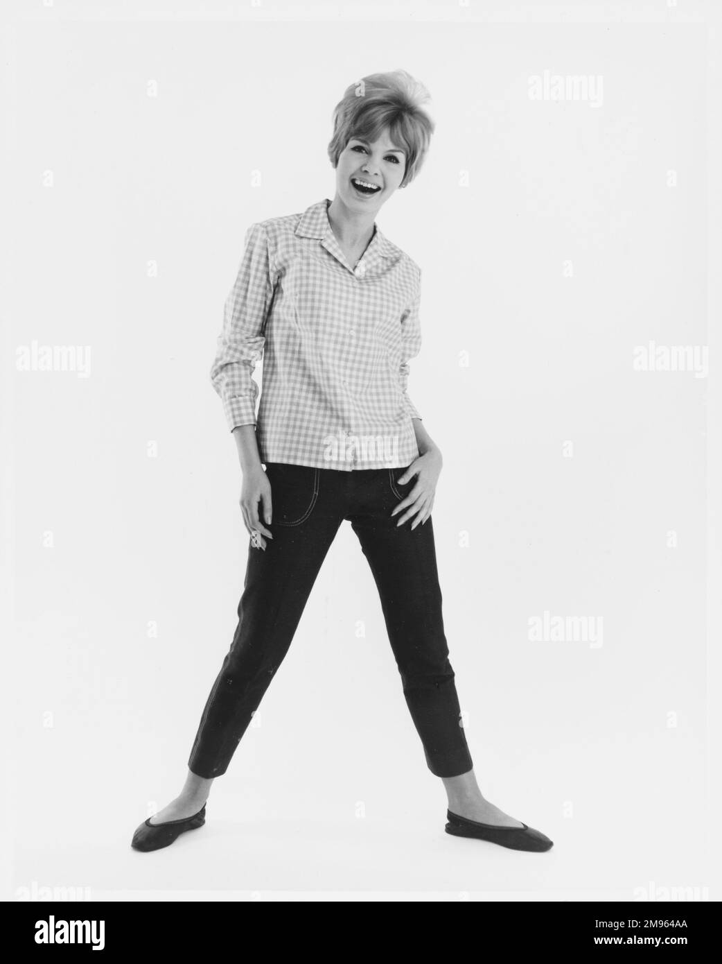 Ritratto a tutta lunghezza di un modello in una camicia a quadri e jeans corti in posa per la fotocamera. Foto Stock
