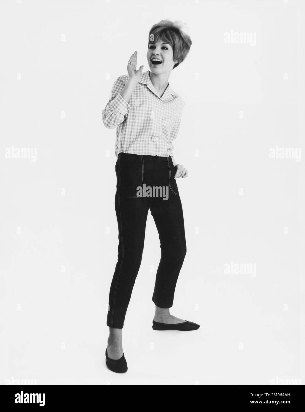 Ritratto a tutta lunghezza di un modello in una camicia a quadri e jeans corti, in posa per la fotocamera. Foto Stock